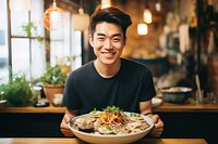 Japanese food vlogger holding a plate of food smile meal dish.