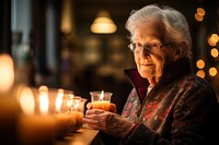The elderly female volunteer lighting glasses candle.