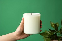Candle packaging mockup holding green hand.