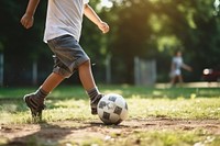 A boy kicks a football outdoors sports shorts.