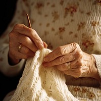 Hands holding wooden knitting needle doing knitting adult white craftsperson.