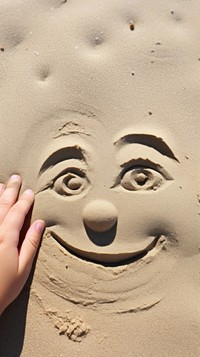 Face doodle finger-drawing sand outdoors nature.