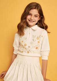 Cheerful kid wearing white embroidered polo sweatshirt and white contrast pleated skirt portrait sleeve blouse.