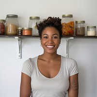 A happy affrican woman standing in the kitchen portrait shelf smile.