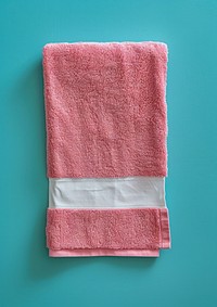 Empty white cotton long rectangle label vertical sewn on the end of flatten pink towel hygiene textile blue.