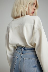 Super close up woman wearing bottom denim faded jeans with empty embroider label on back side fashion blouse sleeve.