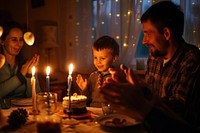 Cheerful family applauding for birthday boy sitting candle light.