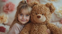 Studio shot of a child hugging a large realistic bear portrait toy representation.