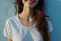 A happy woman wearing white t shirt blue wall hairstyle.