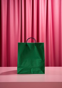 A paper shopping bag put on pink velvet podium backdrop handbag green accessories.