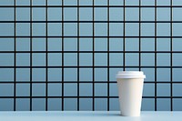 A paper coffee cup is on a black grid fence wall tile blue.
