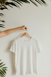 Hand holding hanger with white t shirt t-shirt sleeve blouse.