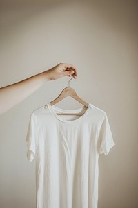 Hand holding hanger with white t shirt t-shirt sleeve blouse.