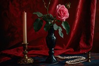 Hot pink rose in tall black vase with candlestick and pearl necklace flower plant red.