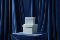 Two stacked white boxes on a podium backdrop blue curtain furniture.