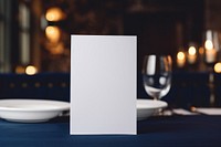 Paper white blank menu card on white plate table glass blue.