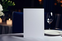 Paper white blank menu card on white plate candle table glass.