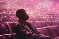 Black man sitting on seats at empty stadium glitter purple pink.