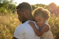 Black man holding his daughter outdoors nature portrait.