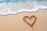 Heart icon written on sand beach wave tranquility.