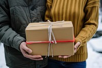 Two people standing outside of home holding one package box cardboard anticipation.