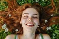Young woman lying down on the field in green grass dandelion portrait smiling.