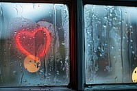 Heart icon written on misted window glass transportation.