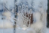 Handprint silhouette written window glass freezing.