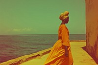 African woman walking on walkpath by sea turban architecture tranquility.