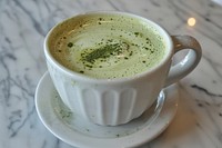 Closeup of a matcha latte coffee saucer drink.