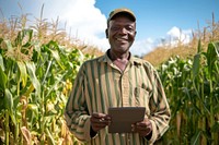 Farmer stands in front of his corn field holding a tablet outdoors adult happy.