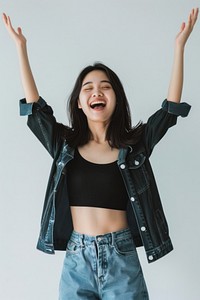 Excited Asian woman raised her hands up laughing jacket smile.