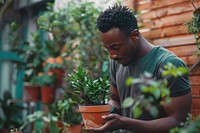 Black man taking care of a plant pot outdoors garden gardening.
