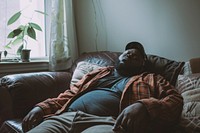 Depressed black chubby man couch furniture blanket.