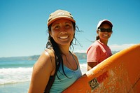Hispanic woman carrying surfboard with her friend on the beach portrait photo photography.
