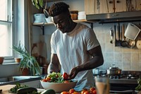 An african american man prepare salad in a kitchen cooking adult food.