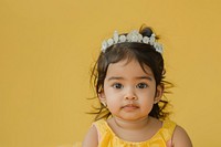 Indian girl toddler wear a crown portrait yellow photo.