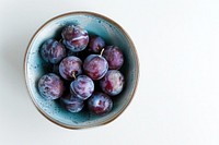 A bowl of plum produce fruit plant.