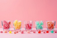 Glassware with different chewy candies on table against color background confectionery medication dessert.