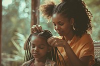 Black mom making braids hair her daughter hairdresser cornrows haircut.