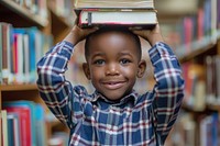 Black child lifts a book and places it on his head library publication reading.