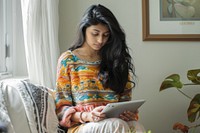 Young woman using tablet computer sitting reading.