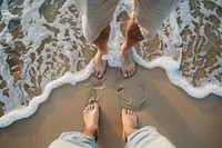 Dad and son standing on beach sea barefoot outdoors.