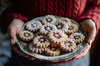 Hands holding a plate with homemade Linzer Cookies cookie food confectionery.