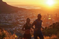 Fit young couple smiling while out for a run together on a scenic trail overlooking a city at sunset running adult togetherness.