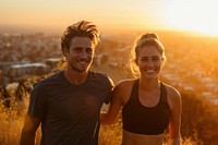 Fit young couple smiling while out for a run together on a scenic trail overlooking a city at sunset outdoors smile adult.