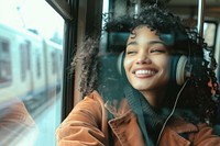 Happy young Ansian woman with curly hair wearing headphones happy train transportation.