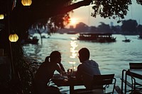 English man and woman dinner at the restuarant in the riverside Chao Phraya River Thailand photo transportation architecture.