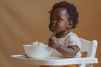African American toddler sitting in a high chair bowl food beverage.