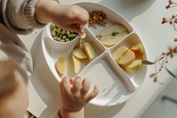 A baby is sitting at the table food cooking produce.